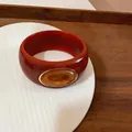 Detailed macro view of a red chunky acrylic bangle featuring an amber oval inset - Orange/Light Yellow