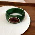 Close-up of dark green marbled acrylic bangle with amber oval centerpiece - Green/Dark Coffee