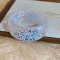 Close-up detail of iridescent geometric shards embedded in a clear resin bangle - White