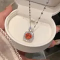 Dettaglio di una collana di lusso con pietra arancione e zirconi in una scatola bianca - Ciondolo Halo Tondo Rosso / Argento