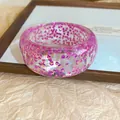 Macro view of a clear resin bangle filled with vibrant pink iridescent glitter details - Purple