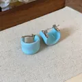 Gros plan montrant la texture en émail bleu clair de ces boucles d'oreilles en U - Bleu / Une Paire