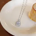 Dettaglio di una collana d'argento con ciondolo in zircone scintillante su un piatto. - Ciondolo Tondo a Doppio Strato Bianco / Argento