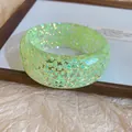 Detailed macro view of a light green resin bangle featuring iridescent shimmer flakes - Green