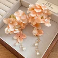 Close-up of peach fabric flower hair clip with dangling pearl tassels and gold rings - Orange