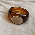 Bold amber marbled acrylic bangle with oval beige resin inlay and gold-tone bezel accent - Coffee/Light Orange