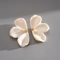 Close-up macro detail of elegant cream resin flower stud earrings with gold centers - Beige