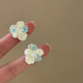 Detailed close-up showing translucent crystal and pearl flower stud earrings on fingers - Silver Earring Post Style / Light Yellow