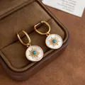 Close-up of gold plated sunburst earrings with mother-of-pearl and turquoise center - Ear Buckle / Gold