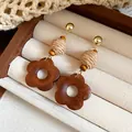 Detail view of ethnic wooden flower drop earrings with raffia beads in a jewelry box - Flower Shape / Brown