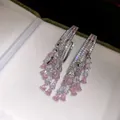 Macro detail of luxury 18k gold plated teardrop tassel earrings with pink zircons. - Silver-Pink