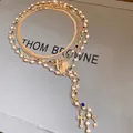 Detailed macro view of a multi-layer gold necklace with pearls and cross pendants - Choker Necklace / Gold