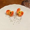 Detailed view of elegant orange fabric flower earrings with cascading pearl tassels. - Yellow