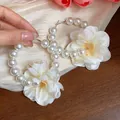 Dettaglio macro di eleganti orecchini a cerchio con fiori in tessuto crema e perle bianche. - Stile Tondo con Fiore in Tessuto(HE31885) / Bianco