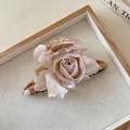 Dettaglio di un grande fermaglio a forma di rosa in tessuto rosa cipria nel vassoio. - caffè