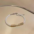 Elegant pearl bracelet with gold zircon bar on a reflective surface detail view. - Gold White (Pearl Style)