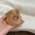 Detailed view of a vintage golden cuff bracelet with intricate woven rope texture - Open Criss Cross / Gold