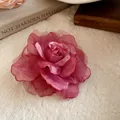 Close-up of a handmade dusty pink mesh fabric rose flower hair clip on soft fabric - Duckbill Hair Clips / Red