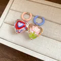 Close-up of dopamine style heart earrings with internal flower and heart patterns. - Colorful