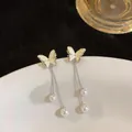 Close-up detail of cream butterfly stud earrings with silver chain tassels and pearl drops. - Silver Pin Butterfly Tassel Style (HE32754) / Beige