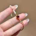 Close-up of 18K gold plated bracelet featuring white pearls and a brilliant red zircon. - Adjustable Bracelet / Gold