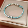 Detailansicht eines blau gewebten Armbands mit zirkonia-besetzten Anhängern auf Box - 16cm / Blau