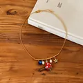 Close-up detail of sweet gold necklace with enamel star, strawberry, and pearl charms. - Gold-Red