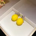 Detailed close-up view of bright yellow lemon stud earrings with sparkling zirconia leaf accents - Earrings / Yellow