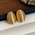Close-up detail of golden minimalist oval stud earrings with fine ribbed texture - Minimalist Oval Style (HE31886) / Gold
