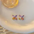 Detailed shot of colorful zircon flower butterfly stud earrings on a ceramic plate - Rose Gold (Multicolor Stone)