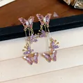 Gros plan d'élégantes boucles d'oreilles papillon en zircone violette sur un écrin - Clip d'Oreille Papillon Doré à Gland (HE31675) / Une Paire / Violet