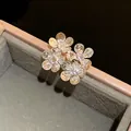 Close-up of sparkling zircon flower ear studs with golden finish and hammered petals - Silver