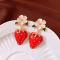 Close-up of exquisite strawberry flower earrings with silver needles on ceramic plate - Red and White