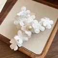 Detailed view of an elegant white fabric flower hair claw clip with a lustrous central pearl - White