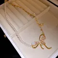Close-up of vintage pearl necklace with bow, bee and flower pendant in jewelry box - Gold-White