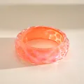 Close-up van iriserende geplooide hars armband met een oranje en roze kleurverloop - Oranje