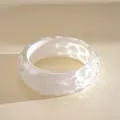 Detailed view of iridescent resin bangle with ripple texture and opalescent finish - White