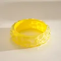 Detailopname van een gele hars armband met een unieke golvende textuur - Geel