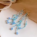 Macro view of blue crystal and bead tassel earrings featuring golden starfish charms for vacation. - Earrings Only / 11.5x2.5cm / Blue