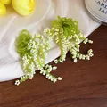 Close-up of handmade beaded lily of the valley earrings with green and white glass beads. - Green