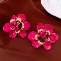 Nahaufnahme von pinkfarbenen Emaille-Blumenohrringen mit goldenen Details am Blütenstempel - Fuchsia
