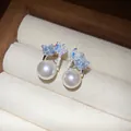 Macro detail of blue zircon butterfly earrings with pearls presented in a cream jewelry box - 30# Silver Pin Silver Blue