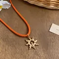 Detail of a sunburst pendant necklace with a bright orange braided rope cord - Gold-Orange