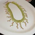 Close-up of handmade lime green beaded necklace with delicate pink flower charms. - Green-Pink