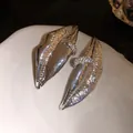 Detailed macro view of silver-tone textured lip-shaped earrings with rhinestone accents. - Silver