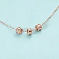 Primo piano di collana in oro rosa con tre perle distanziatrici cilindriche cave - Oro rosa