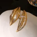 Close-up detail of vintage lip-shaped golden earrings with sparkling crystal accents - Gold
