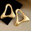 Primo piano dettagliato di orecchini triangolari cavi placcati in oro con finitura liscia - Oro
