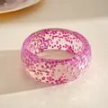 Detail of a transparent resin bangle featuring pink geometric glitter fragments - Purple