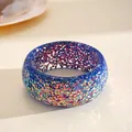 Detail view of a vibrant iridescent resin bangle with colorful geometric glitter texture. - Dark Blue